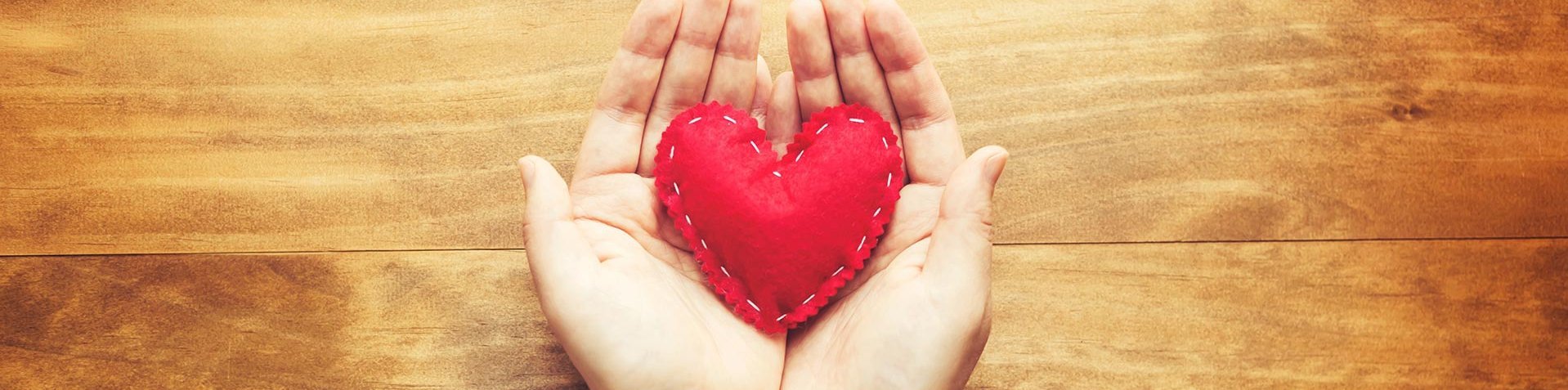 Symbolbild: Hände halten ein Herz aus rotem Filz