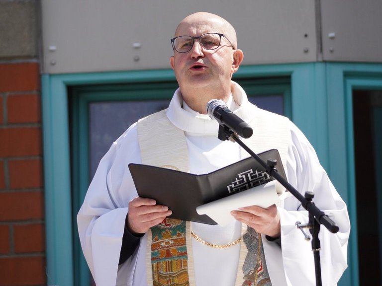 Ein Pater des Deutschen Ordens im Messgewand steht am Mikrofon und liest aus einer schwarzen Mappe.