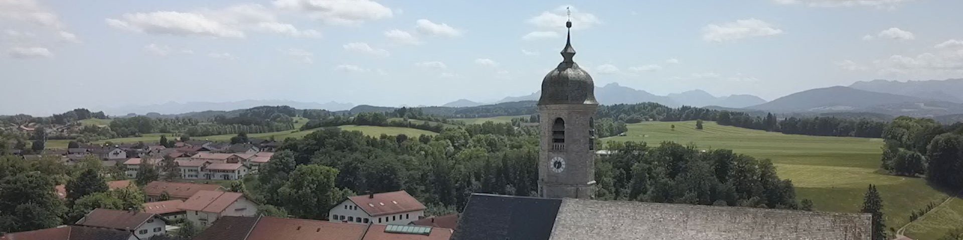 Kirchturm mit Alpen im Hintergrund