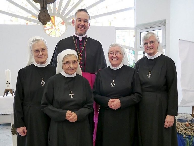 Pater mit Ordensschwestern in Kirche