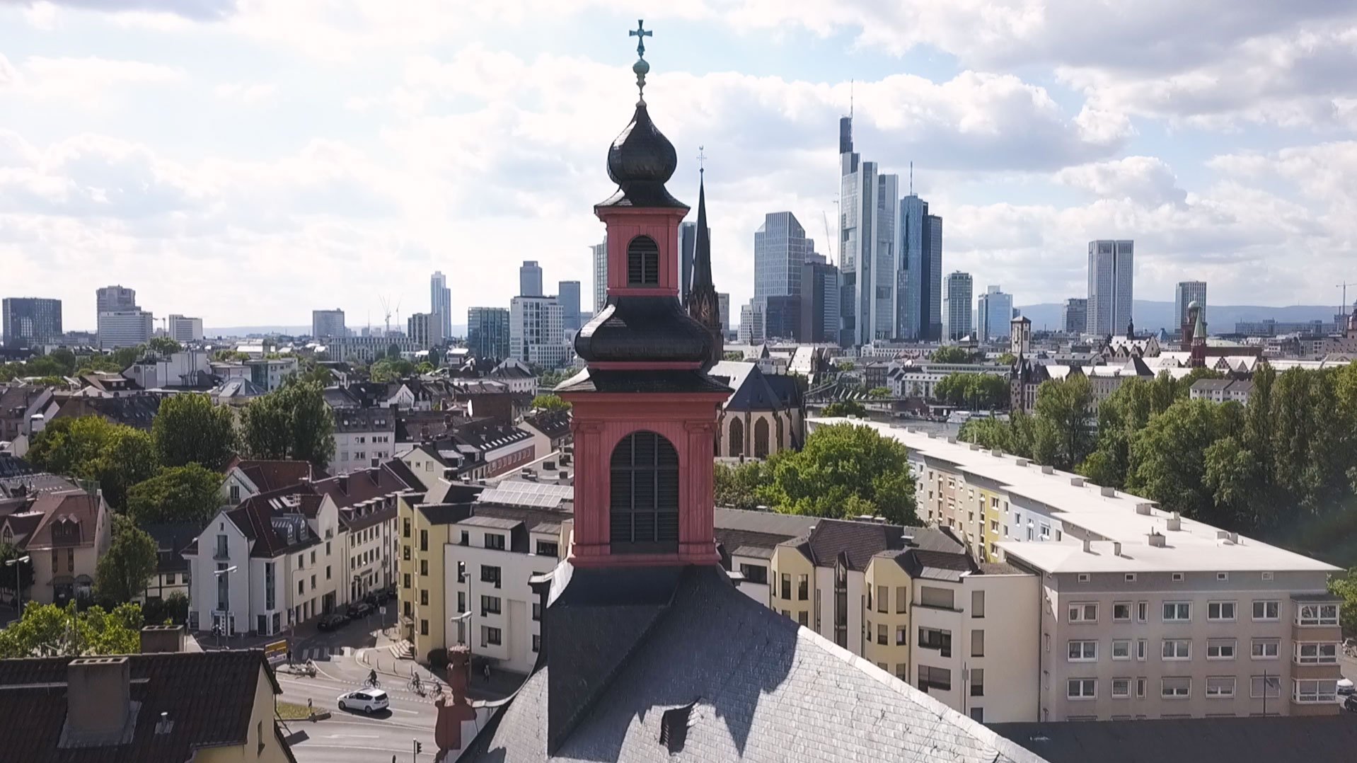 Kirchturm mit Hochhäusern im Hintergrund